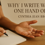 Open hand reaching across a wooden desk beside a notebook.